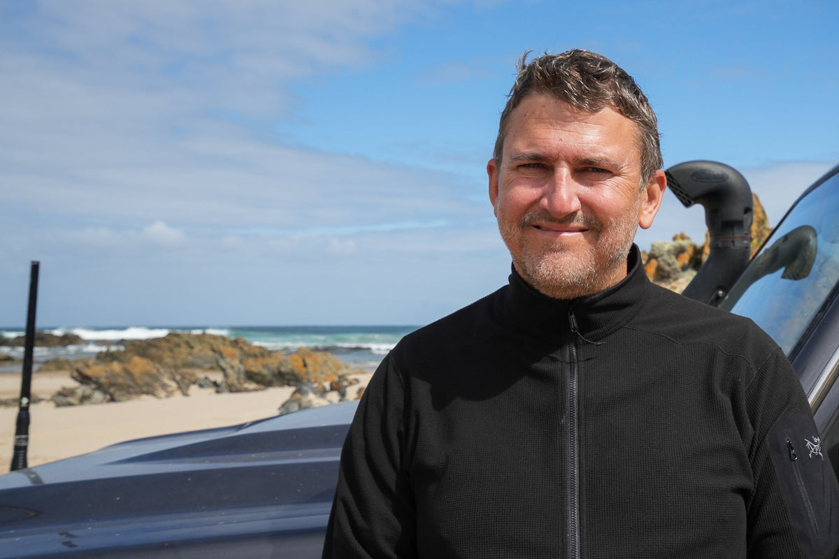 Adventure marketing consultant Mike Collister standing beside his 4WD on a beach near Sandy Cape on Tasmania's rugged and remote north-west coast